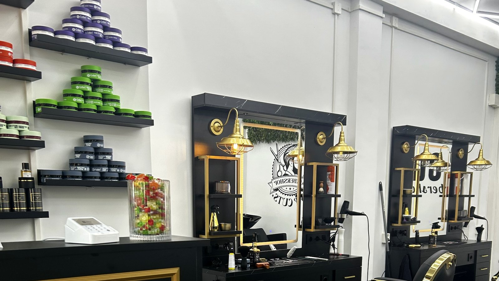 Spiegels met gouden wandlampen en haarproducten bij Barbershop VIP Cuts