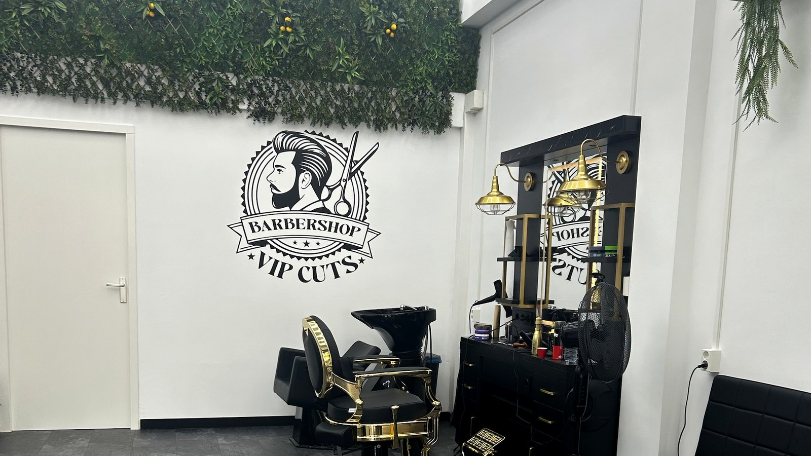 Kappersfauteuil met wasunit en groene plantenwand bij Barbershop VIP Cuts